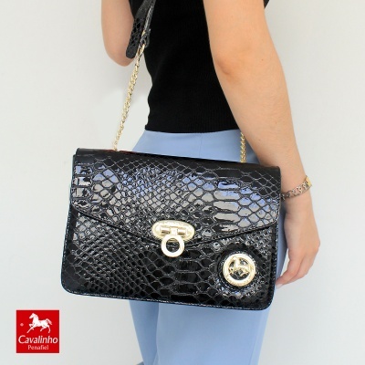 Mala preta com padrão tipo pele de crocodilo e fecho dourado