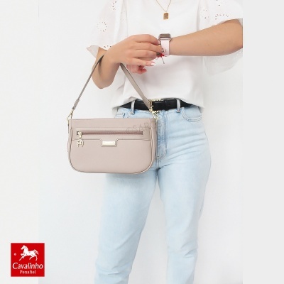Bolsa pequena bege com alça de ombro fina usada por mulher