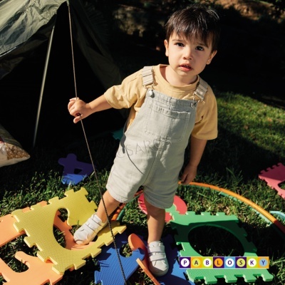 Criança com roupa casual luz ao ar livre em chão com peças coloridas.