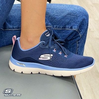 Tênis desportivo azul Skechers com sola branca e detalhes cor-de-rosa usado numa perna com calças de ganga azul