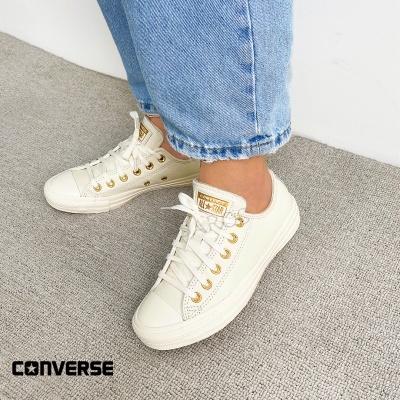 Ténis Converse All Star de cano baixo em tom cru com ilhós dourados e etiquetas visíveis na língua