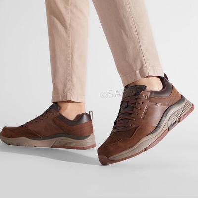 Ténis masculinos castanhos com sola robusta usados com calças bege