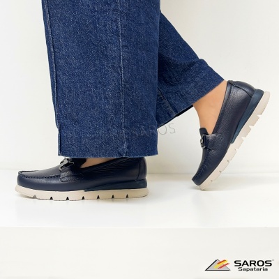 Sapatos mocassins pretos de couro com sola branca e calças de ganga