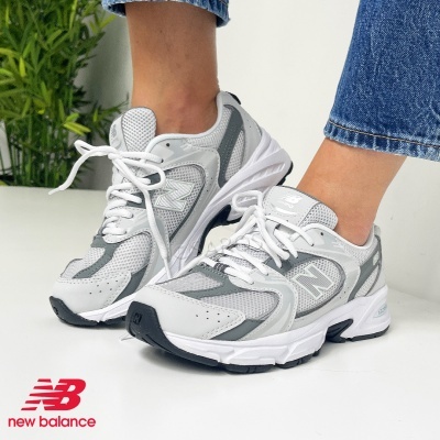 Ténis cinzentos e brancos New Balance em pessoa, vista lateral