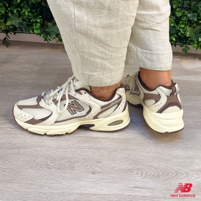 Ténis New Balance 530 bege e castanho, detalhes em mesh e sola ABZORB no chão de madeira