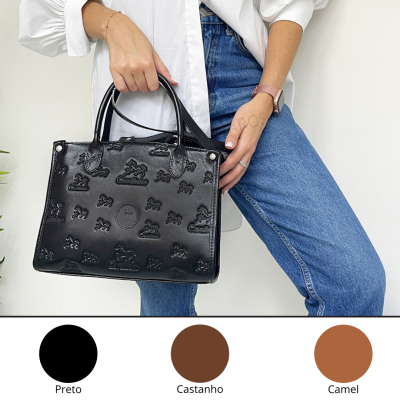 Mala preta em couro com padrões em relevo e mulher a segurá-la