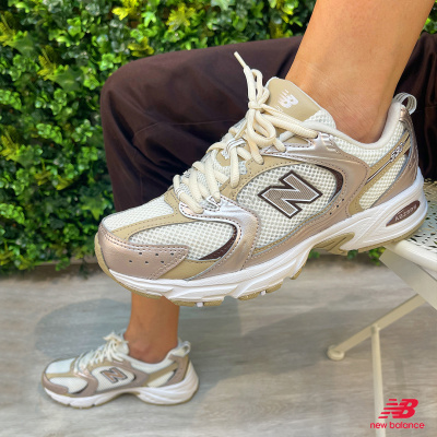 Sapatilhas New Balance 530 creme e bege com detalhes metálicos em ambiente exterior