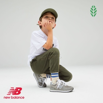 Criança agachada com roupa casual e ténis New Balance cinzentos