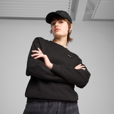 Pessoa de casaco e boné pretos com logótipos PUMA em fundo interior cinzento