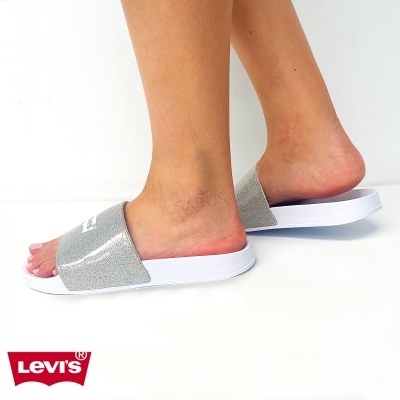 Chinelos prateados e brancos Levis usados em pés femininos