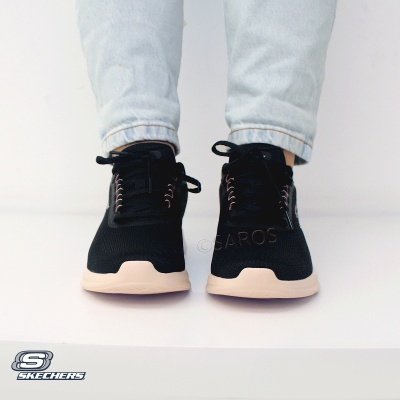 Ténis pretos Skechers com sola clara usados com jeans claros