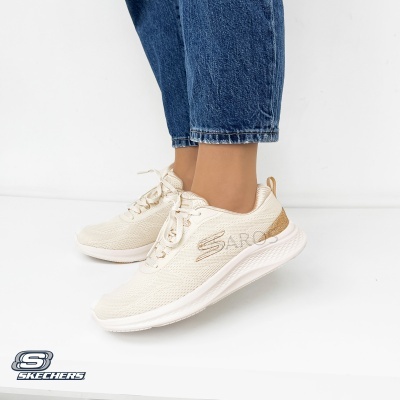 Ténis creme Skechers com detalhes dourados e sola branca usada com calças de ganga azul