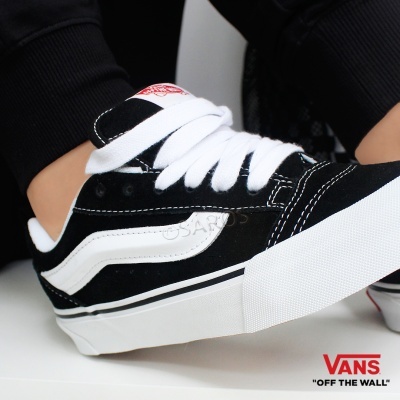 Sapatilhas Vans pretas e brancas com etiqueta vermelha