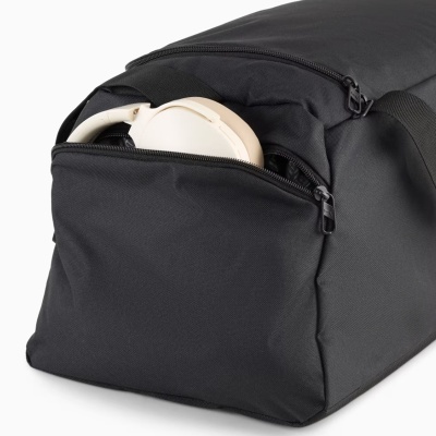 Mala preta com bolso frontal aberto e auscultadores creme visíveis