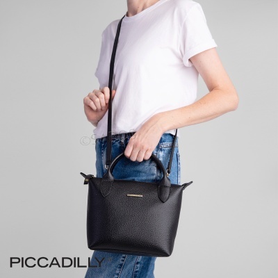 Mala preta pequena com alças, em modelo com roupas casuais, fundo cinza.