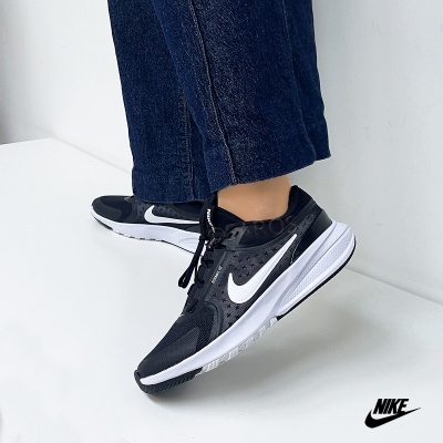 Ténis Nike pretos com detalhes brancos usados com calças de ganga