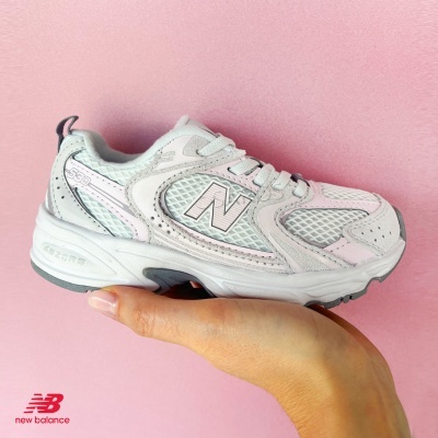 Ténis desportivo New Balance cinza claro e rosa pastel sobre fundo rosa