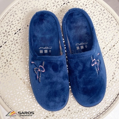 Chinelos de quarto azuis com bordado rosa sobre mesa branca decorada