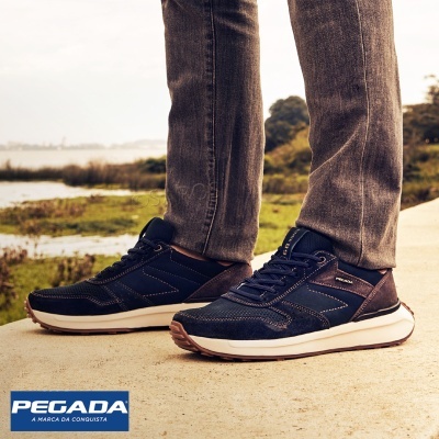 Ténis azuis escuros com sola branca junto a caminho exterior e vegetação