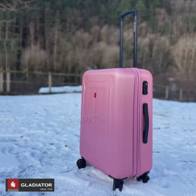 Mala de viagem rígida cor de rosa com rodas e puxador, em paisagem nevada