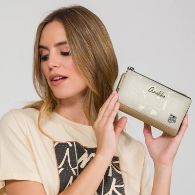 Mulher segurando carteira bege com fecho de correr e textura em relevo