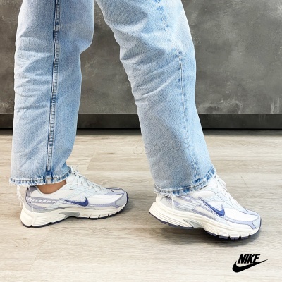 Ténis Nike brancos com detalhes em roxo e azul e jeans azuis
