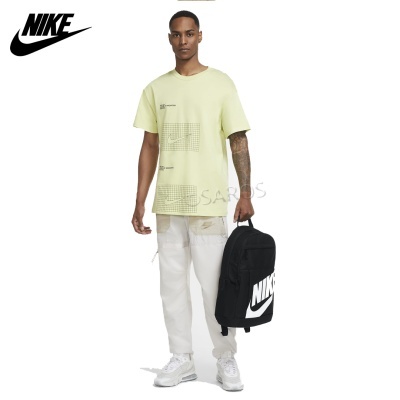 Homem com t-shirt amarela clara, calças brancas, sapatilhas brancas e mochila preta NIKE