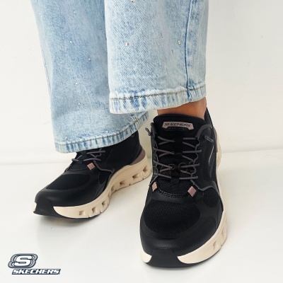Sapatilhas pretas Skechers com sola branca e calças de ganga azuis claras