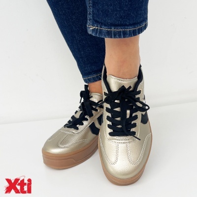 Ténis dourados com atacadores pretos e sola castanha em fundo branco.