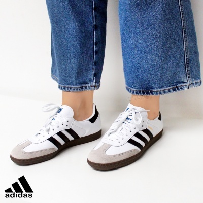 Ténis Adidas brancos com riscas pretas e calças de ganga azul