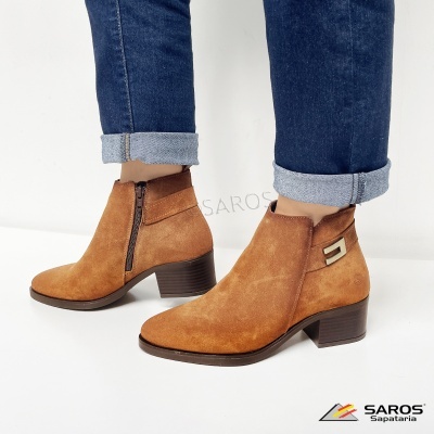Botins castanhos de camurça com fecho lateral e salto médio, usados com jeans dobrados.