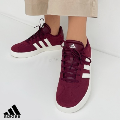 Ténis Adidas bordeaux com riscas brancas e sola branca num fundo branco