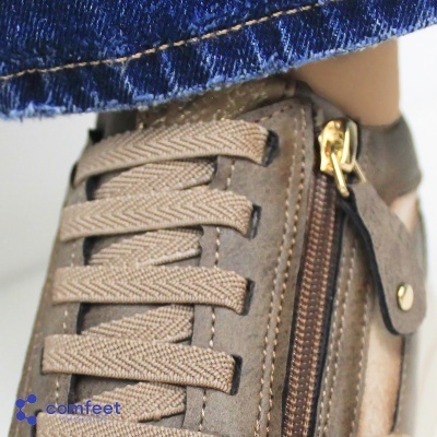 Ténis castanhos com atacadores grossos e fecho dourado ao lado, material semelhante a camurça