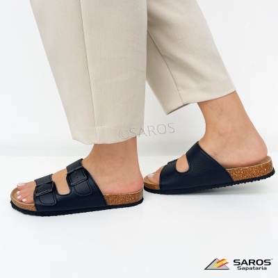 Sandálias slides pretas com duas tiras e fivelas, solado cortiça e borracha, calças bege claro