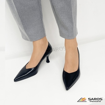 Sapatos pretos de salto alto em pele brilhante com calças cinza.