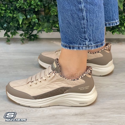 Tênis Skechers Slip-Ins bege com detalhe animal print e sola branca usados com calças de ganga.