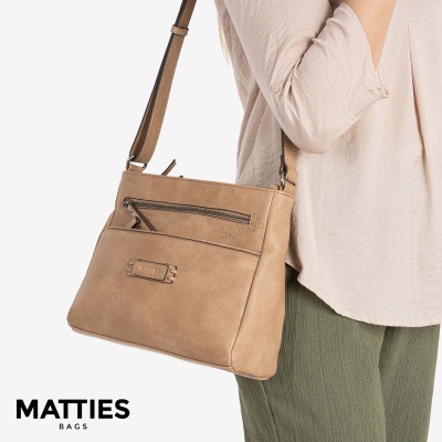 Mala de ombro castanho claro de couro com fecho zip frontal, usada com camisa rosa clara e calças verdes.