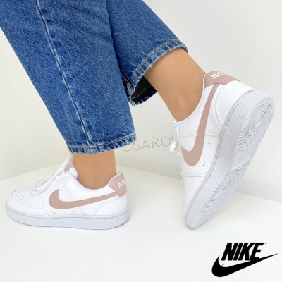 Ténis Nike brancos com detalhes rosa e calças de ganga em fundo branco