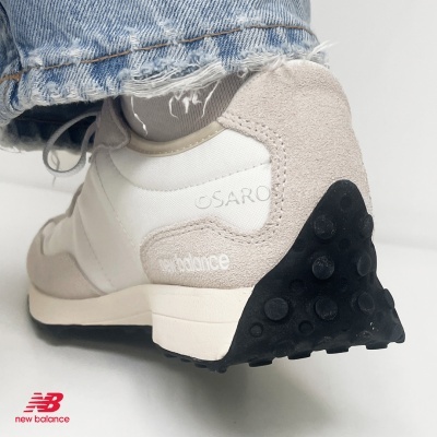 Ténis New Balance branco e bege com sola preta e logo New Balance vermelho no fundo