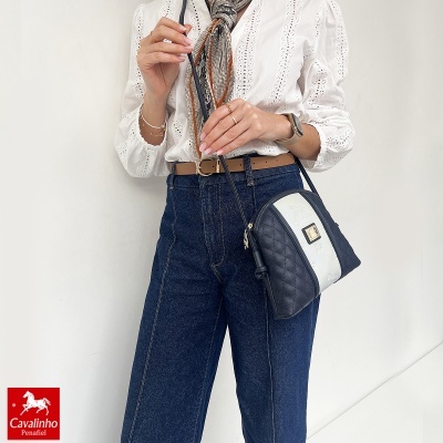 Mala tiracolo preta e branca Cavalinho com camisa branca e jeans azuis