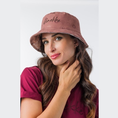 Mulher com chapéu de balde rosa e camiseta bordeaux com logótipo Anekke