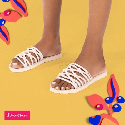 Chinelos brancos Ipanema com tiras entrelaçadas em fundo amarelo com decoração colorida