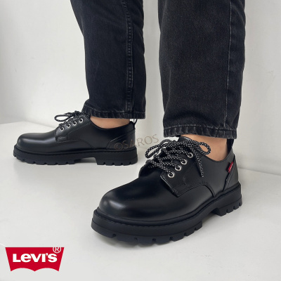 Sapatos pretos em pele com sola grossa e atacadores com pontos brancos