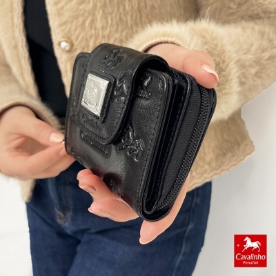 Carteira preta em pele com relevo da marca Cavalinho segurada por uma pessoa