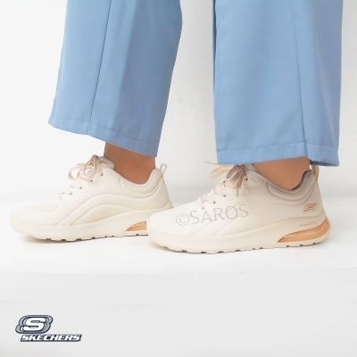 Ténis Skechers creme com detalhes em bege e sola branca usados com calças azuis claras