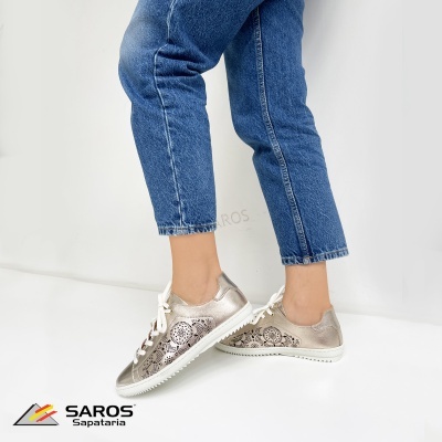 Ténis femininos prateados com padrão floral usados por pessoa com calças jeans azuis