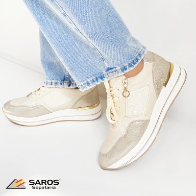 Ténis femininos bege e branco com detalhes dourados e fecho lateral, usados com jeans azul claro