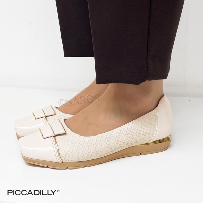 Sapatos femininos rasos cor bege claro com laço e detalhe dourado, usados com calças pretas