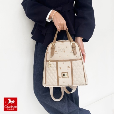 Mala bege com padrão Cavalinho e detalhes castanhos segurada por pessoa