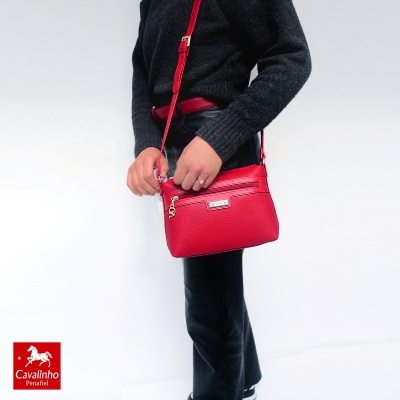 Mala vermelha de pele com alça e fecho dourado, usada ao ombro